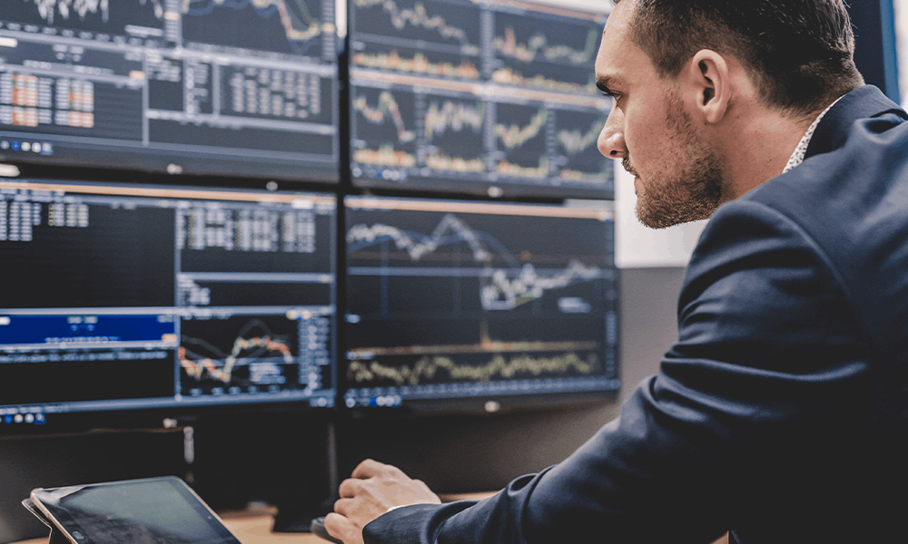 Man looking at stocks on many computers